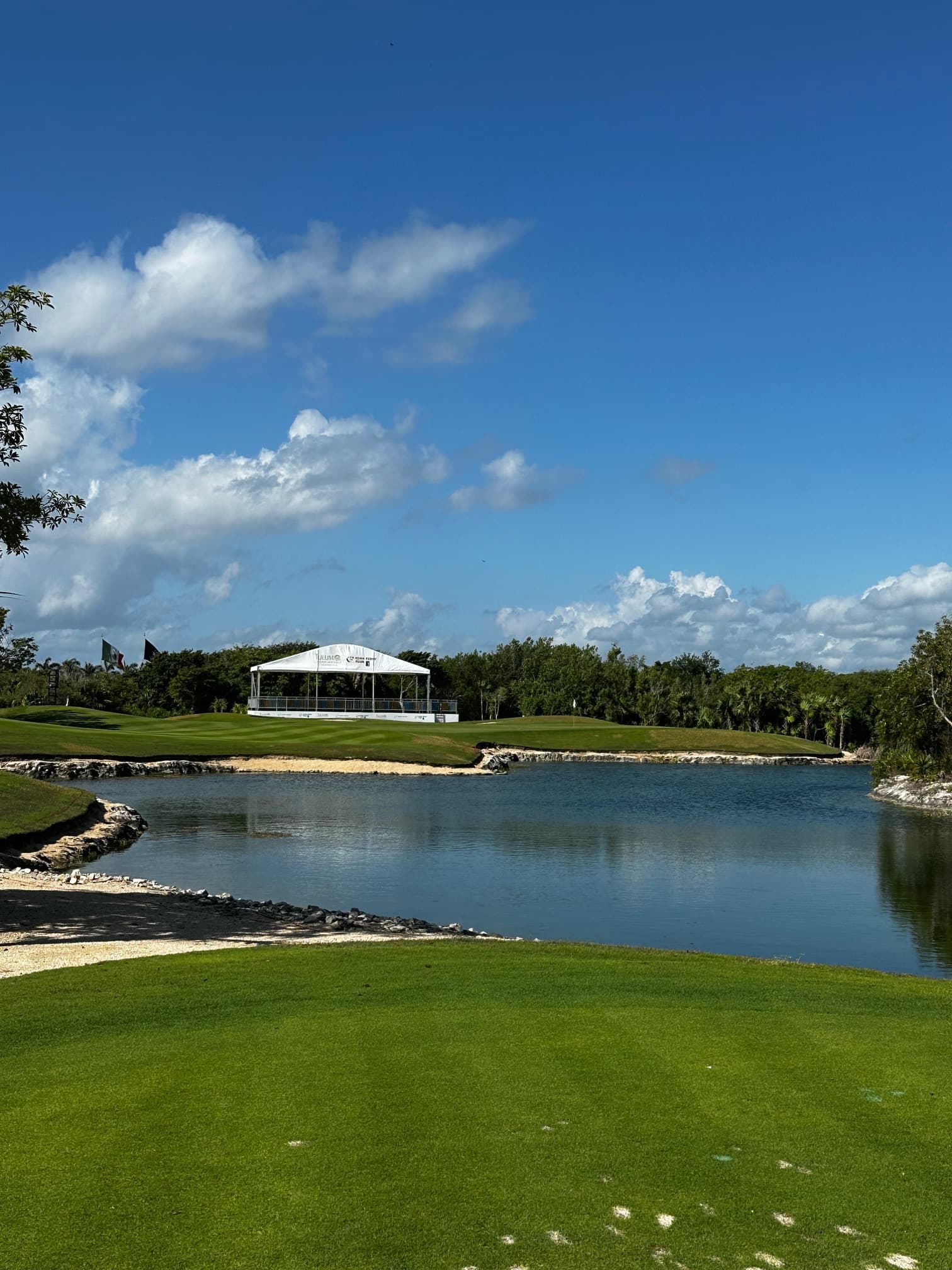 Panoramic view of a tournament hole with water hazard and grandstands